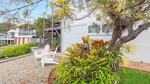 Una casa moderna con un espacio de estar cubierto al aire libre, una escalera y un jardín cuidado.
