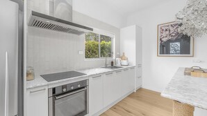 Una cocina moderna con armarios blancos, horno empotrado, cocina y una ventana que proporciona luz natural.