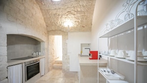 Una cocina con pared de piedra, horno empotrado y encimera con lavabo.