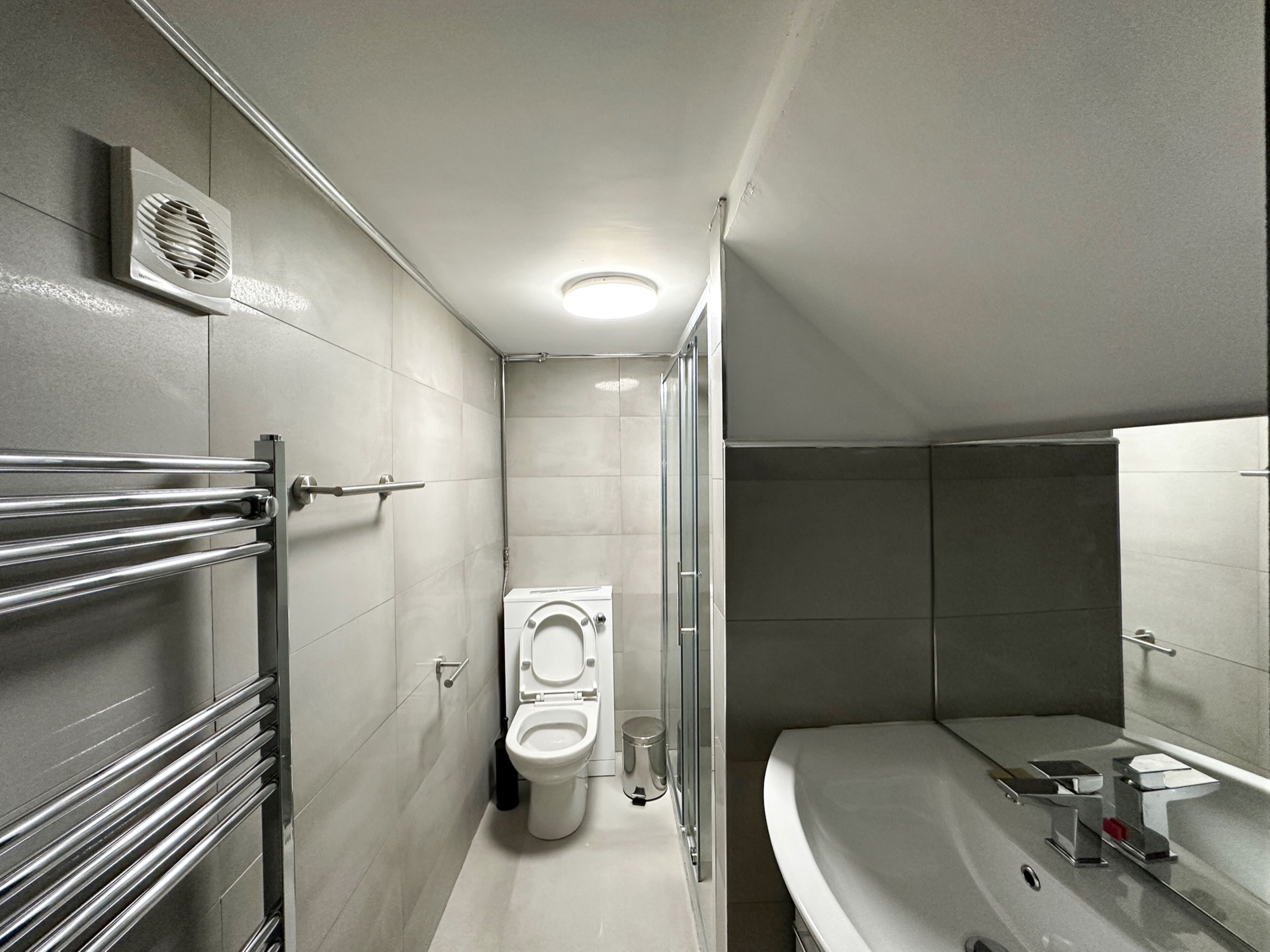 Een moderne badkamer met toilet, douche en bad.