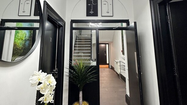 Ein Flur mit einer modernen Leuchte, einem Blumentopf und einer Treppe, die in einen weiteren Bereich führt.