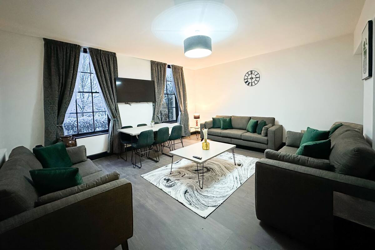 Uma sala de estar com sofá, mesa de centro e televisão na parede.
