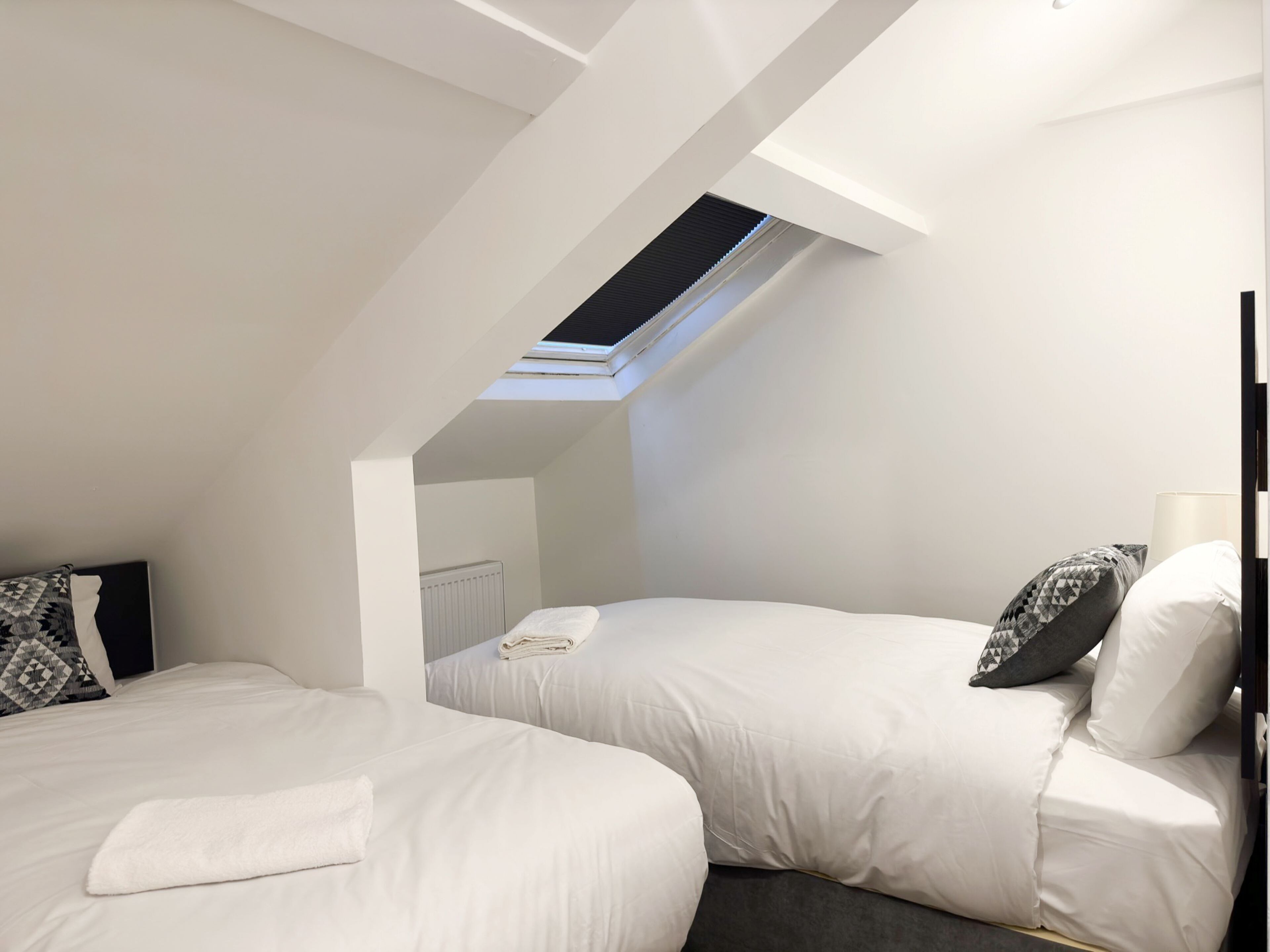 Ein modernes Schlafzimmer mit zwei Betten, einem Oberlicht und einer Heizung.