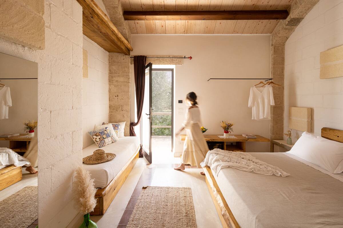 A bedroom with two beds, a wooden ceiling, and a large window.