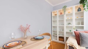 Ruokailutila, jossa on pyöreä pöytä, kaksi tuolia ja valkoinen hyllykaappi.