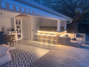 A covered outdoor area with a bar, seating, and a patterned floor.
