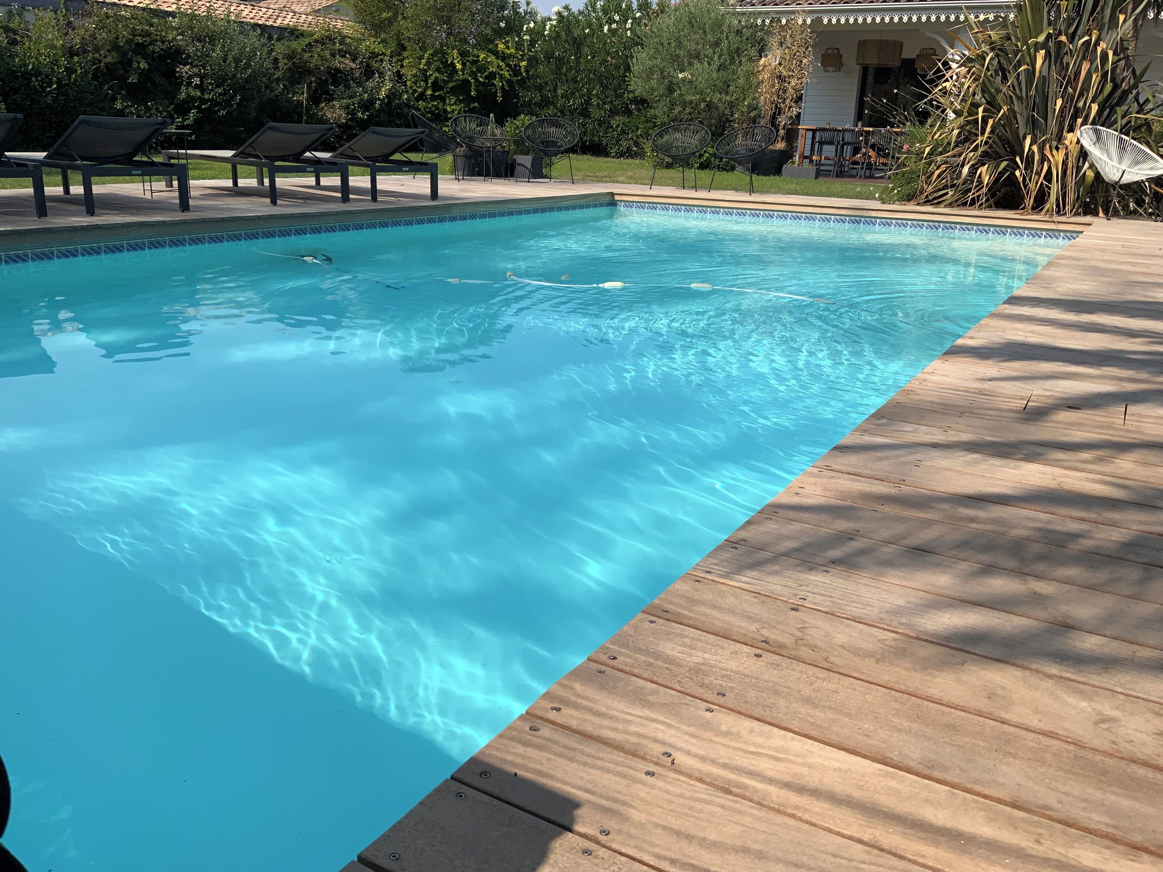 Una piscina cristalina con sillas de descanso y una terraza de madera.