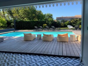 A poolside area with lounge chairs, a pool, and a patterned floor.