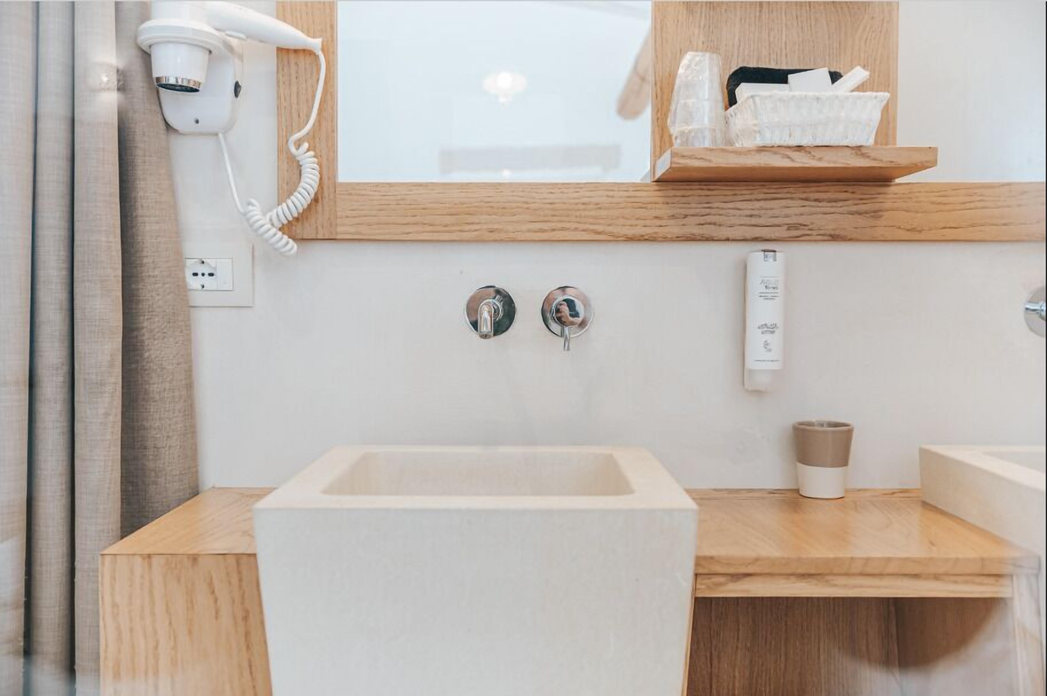 Een moderne badkamer met een grote spiegel, een haardroger, een wastafel en een handdoekhouder.