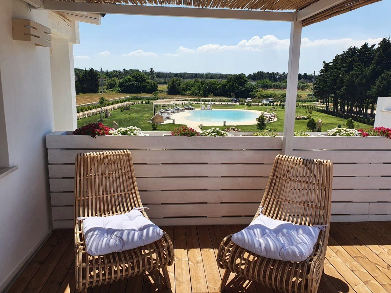A wooden deck with two wicker chairs and a white railing.