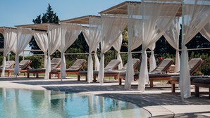 Zona de piscina con tumbonas y toldos.