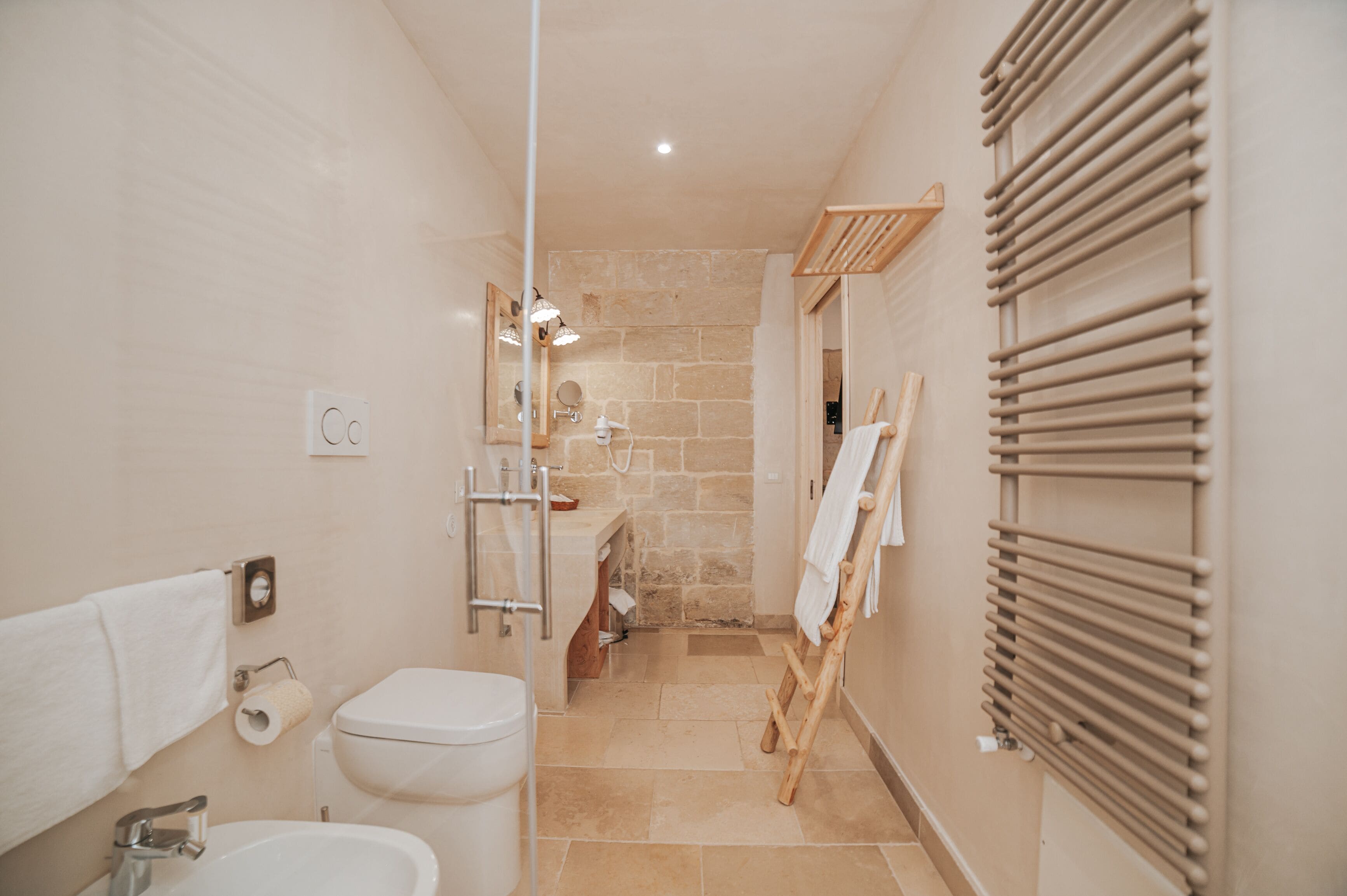 A bathroom with a toilet, sink, towel rack, and a wooden drying rack.