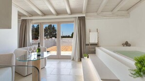 Una sala moderna con una mesa de vidrio, sofá y vistas a una terraza de madera y árboles.