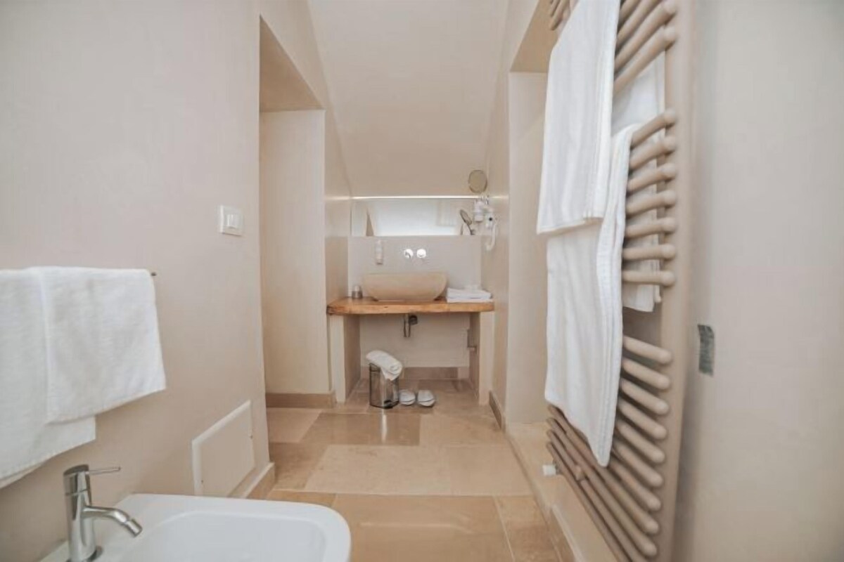 Un baño estrecho con lavamanos, espejo y perchero.