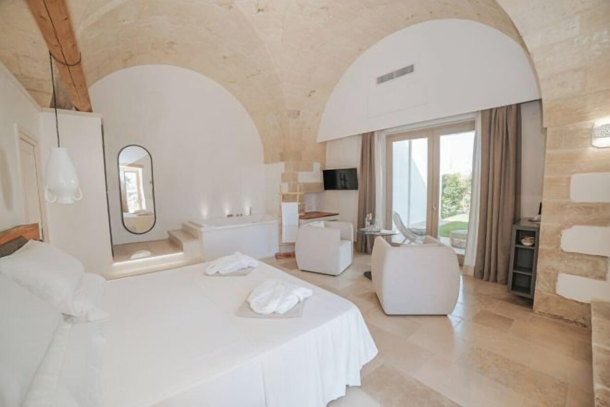 Quarto com cama grande, área de estar e televisão.