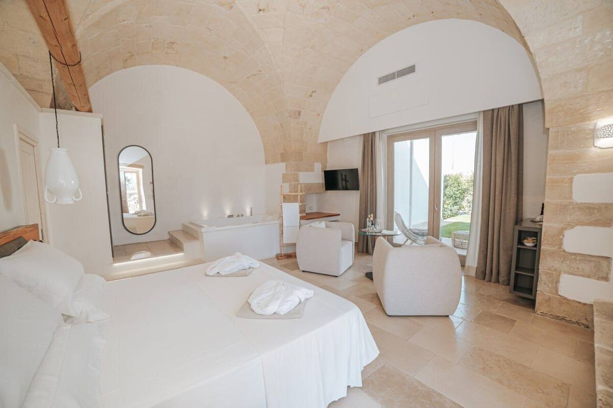 A spacious bedroom with a large bed, a sitting area, and a view of the outdoors.