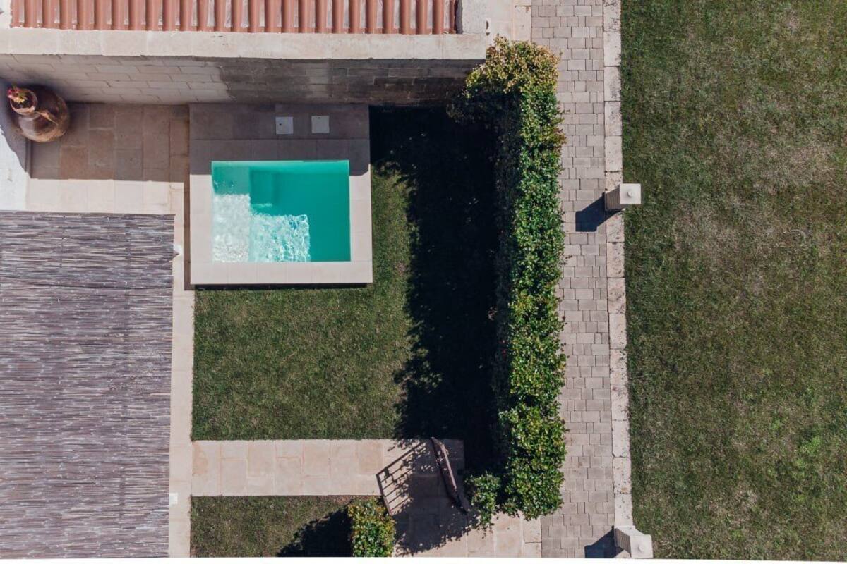 An aerial view of a property with a swimming pool, a patio area, and a well-maintained lawn.