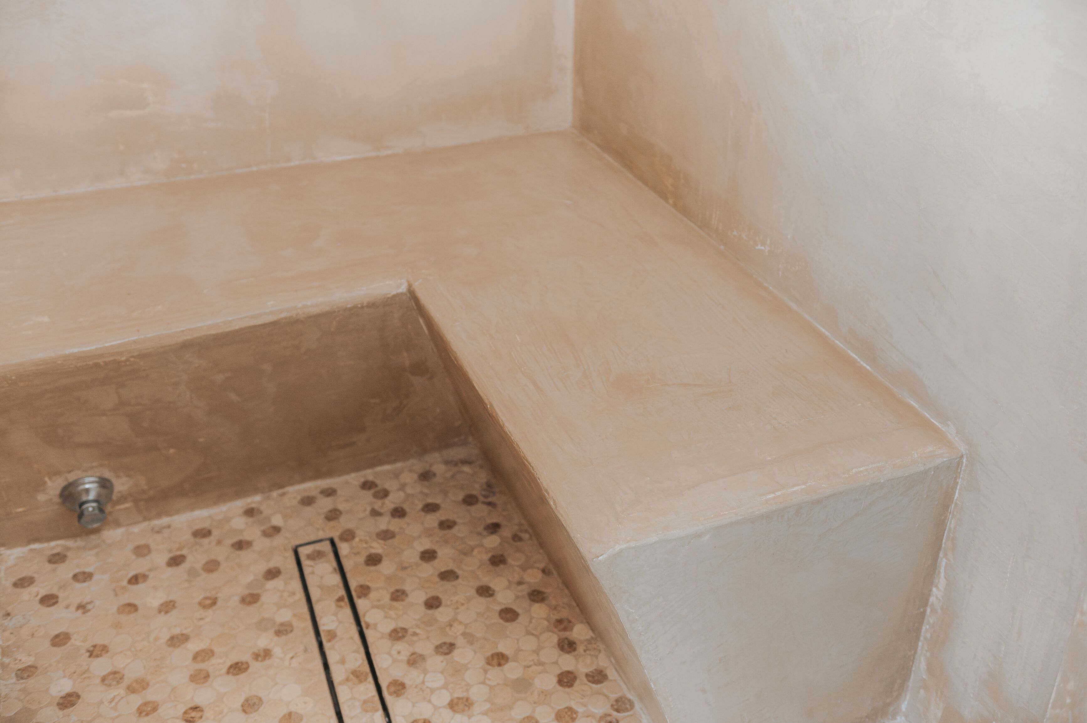 Una esquina de una habitación con suelo de baldosas beiges y pared blanca.