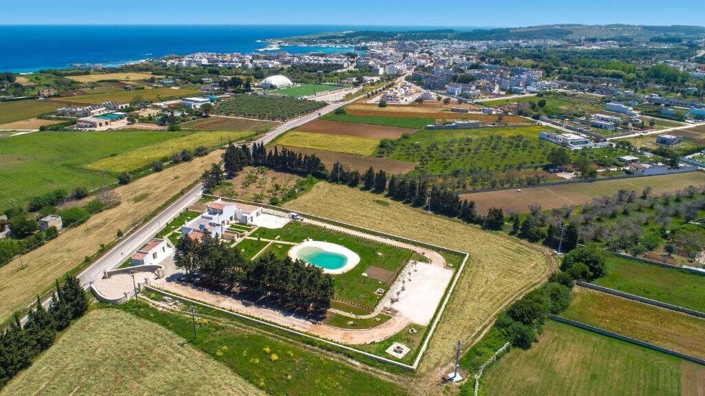 Luchtbeeld van een kustplaats met een groot park, inclusief een zwembad, omgeven door woon- en bedrijfsgebouwen.