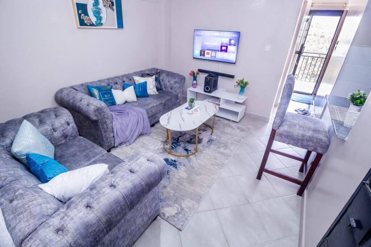 A living room with a grey sofa, a coffee table, and a TV mounted on the wall.