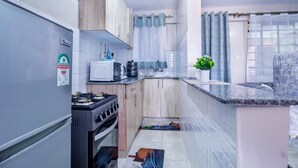 Una cocina compacta con estufa a gas, microondas y pileta.