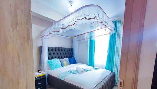 Un dormitorio con cama a cuatro postes, una mesita de noche con lámpara y un tapete verde en el suelo.