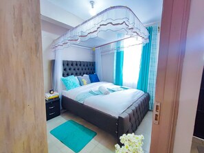 Une chambre à coucher avec un lit à baldaquin, une table de chevet avec une lampe et un tapis vert sur le sol.