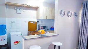 Una cocina compacta con microondas integrado, una pequeña encimera y dos taburetes.
