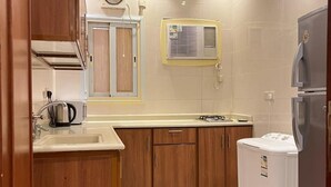Eine Küche mit Holzschränken, einem Einbauofen, einer Spüle und einem Kühlschrank.