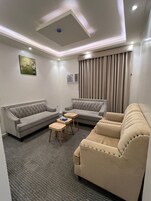 Una sala moderna con un sofá seccional gris, un sofá beige y una pequeña mesa de centro de madera.