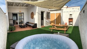 A backyard with a hot tub, a wooden table, and a barbecue grill. - Preciosa Casa Rural en El Ronquillo (El Ronquillo)
