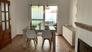 A dining area with a table set for four, chairs, a vase of flowers, and a view of a garden through a window. - Preciosa Casa Rural en El Ronquillo (El Ronquillo)