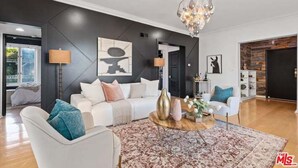 A modern living room with a white sofa, a coffee table, and a chandelier.