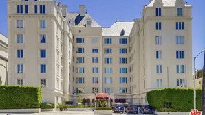 A large, multi-story hotel with a symmetrical facade, numerous windows, and a central entrance with a red canopy.