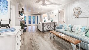 A spacious living area with a wooden floor, a sofa, a coffee table, and a ceiling fan. - 302 Charleston by AvantStay | Stunning Private Pool (Isle Of Palms)
