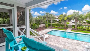 A pool area with turquoise chairs and a view of a well-maintained garden and neighboring houses. - 302 Charleston by AvantStay | Stunning Private Pool (Isle Of Palms)