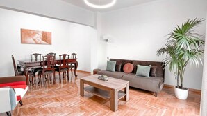 Ein Wohnzimmer mit Essbereich, einer Couch, einem Couchtisch und einem Blumentopf.