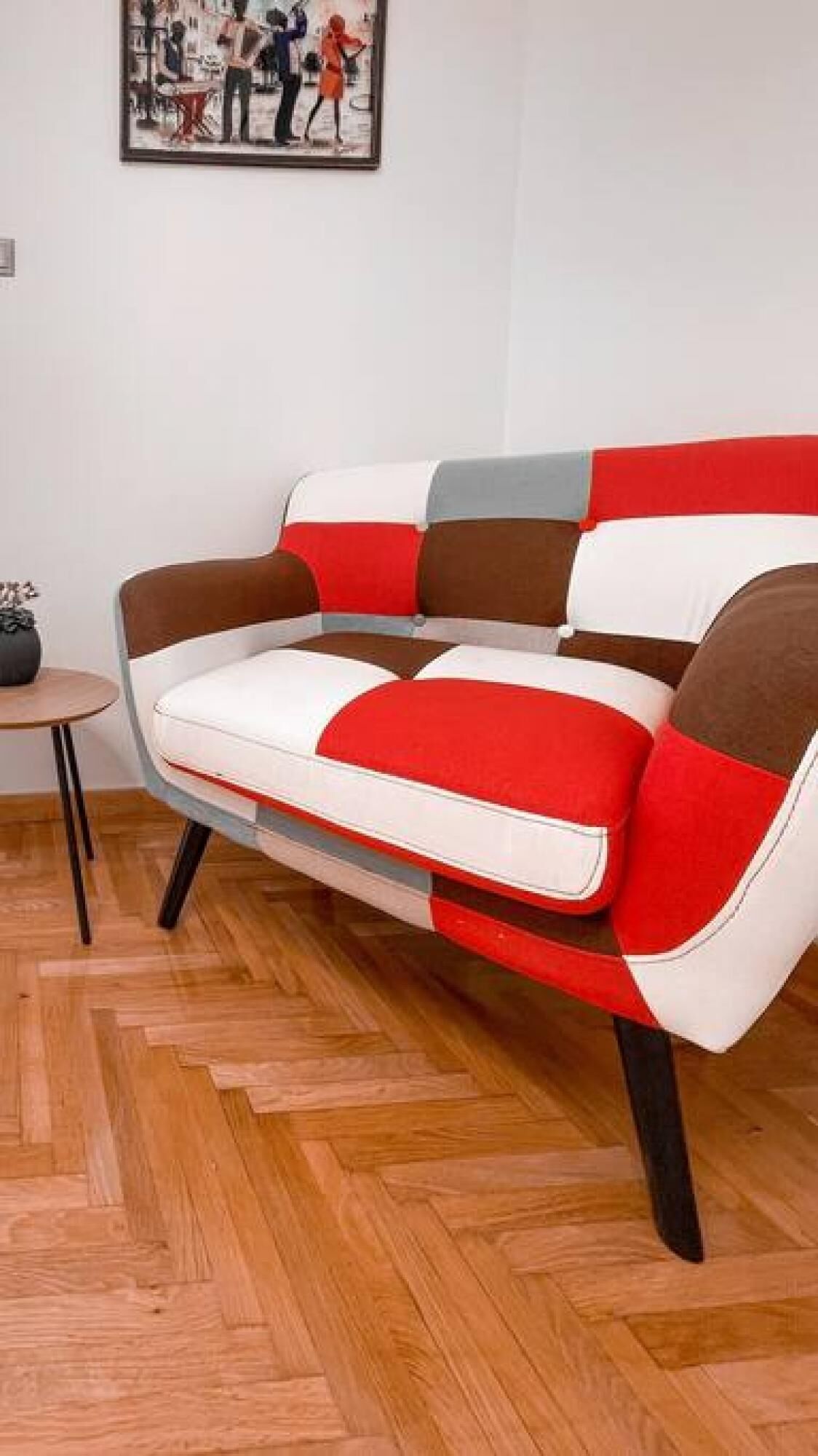 A modern sofa with a geometric pattern in a room with wooden parquet flooring.