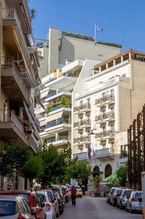 A multi-story building with balconies, parked cars, and a clear sky. - Penthouse - Amazing View in the Center of Athens (Athens)