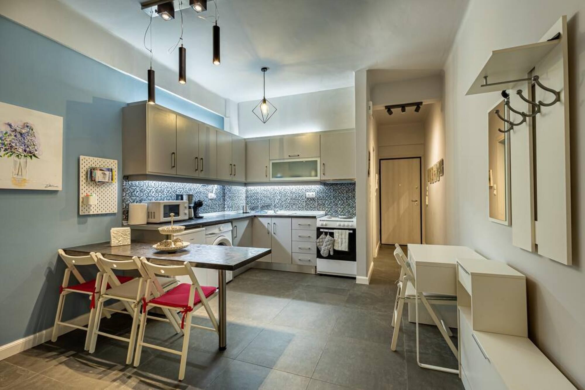 Cozinha moderna com área de refeições, destacando uma ilha central, luminárias pendentes e backsplash revestido de azulejos.
