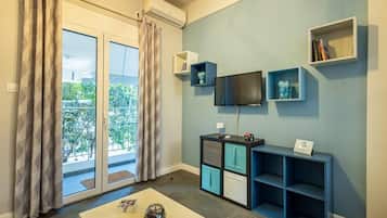 Uma sala de estar moderna com uma porta de vidro deslizante que dá para uma varanda, uma TV de tela plana fixada na parede e uma TV menor sobre um suporte.
