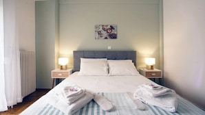 Et hotelværelse med en seng, to sengeborde med lamper, en radiator og et billedværk hængt på væggen.