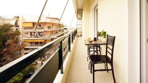 En balkon med et bord og stole, der kigger ud over et boligområde med høje bygninger.