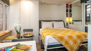 A bedroom with a bed, bedside table, and a window. - Cozy Nest at Acropolis Footsteps (Athens)