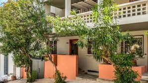 A two-story building with a balcony on the upper floor, surrounded by greenery and a clear sky. - Cozy Nest at Acropolis Footsteps (Athens)