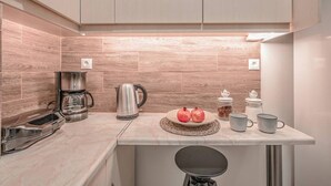 A modern kitchen with a marble countertop, stainless steel appliances, and a potted plant. - Bohemian Chic 1BR Apartment in the Heart of Athens (Athens)