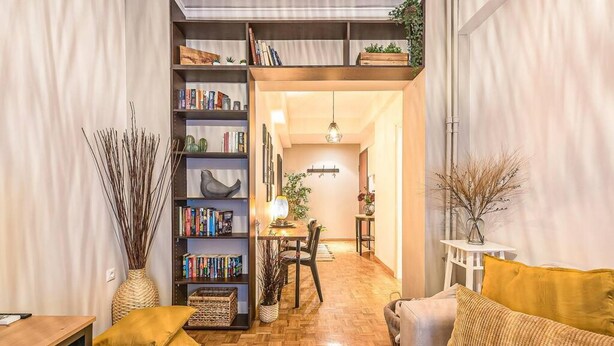 A cozy living room with a wooden floor, a sofa, a bookshelf, and a dining area. - Bohemian Chic 1BR Apartment in the Heart of Athens (Athens)