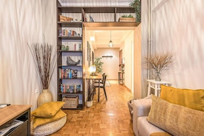 Een gezellige woonkamer met houten vloer, een bank, een boekenkast en een eethoek.