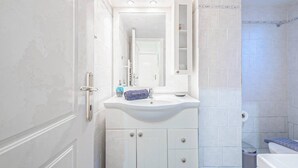 A bathroom with a white sink, mirror, and cabinet. - Bohemian Chic 1BR Apartment in the Heart of Athens (Athens)