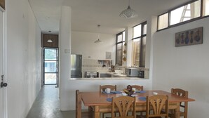 Une cuisine moderne avec un coin repas, comprenant une table et des chaises en bois, un réfrigérateur et une cuisinière.